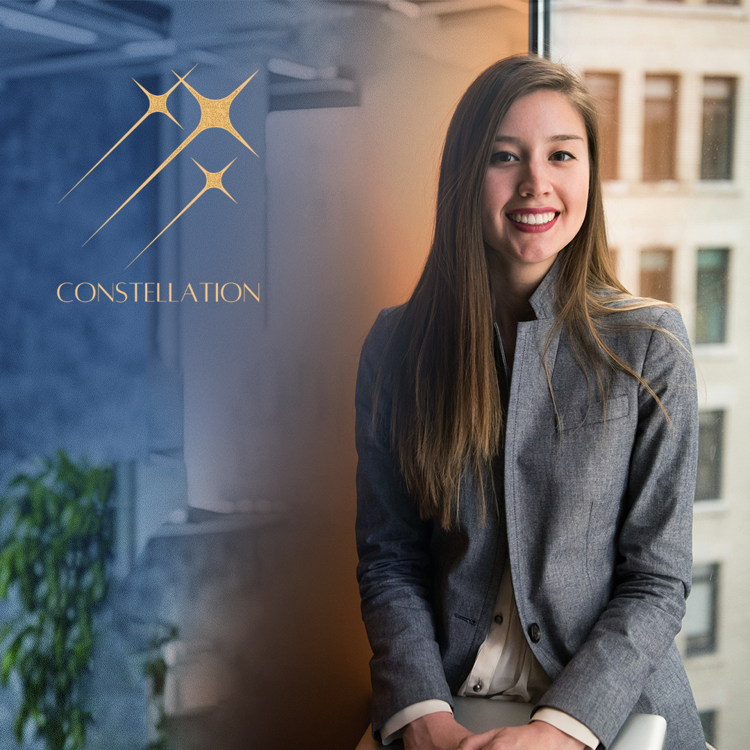 Constellation gold emblem overlay on refined portrait of composed authority in tailored grey against a metropolitan backdrop.