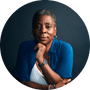 Ursula Burns, former CEO of Xerox and VEON, poised in white tailoring against deep indigo, thoughtful hand at chin.